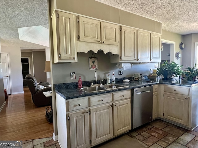 kitchen featuring stainless steel dishwasher, a textured ceiling, a peninsula, a sink, and dark countertops