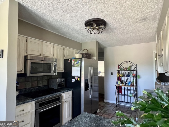 kitchen featuring dark countertops, white cabinets, appliances with stainless steel finishes, and baseboards