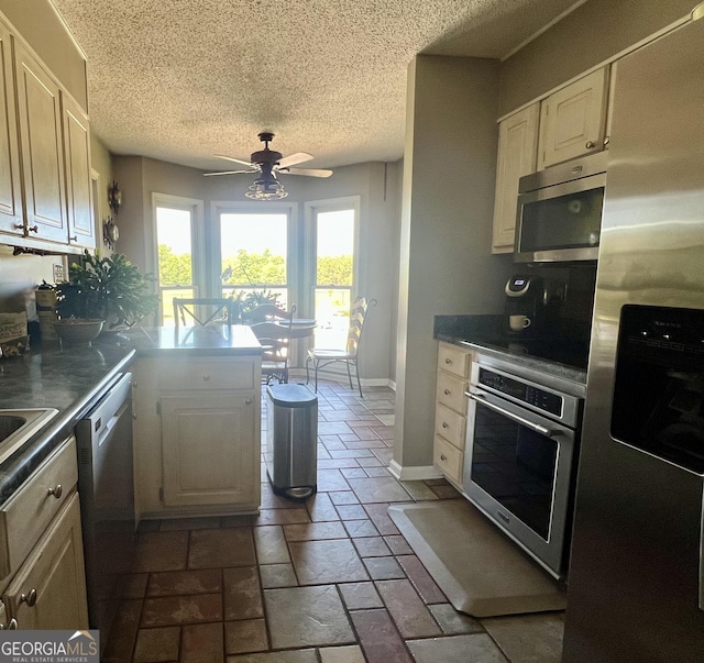 kitchen featuring a peninsula, a textured ceiling, a ceiling fan, white cabinetry, and stainless steel appliances