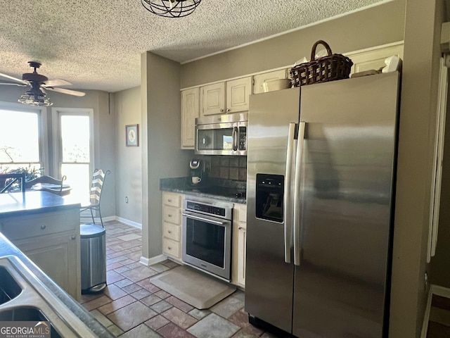 kitchen with baseboards, a textured ceiling, a ceiling fan, white cabinetry, and stainless steel appliances