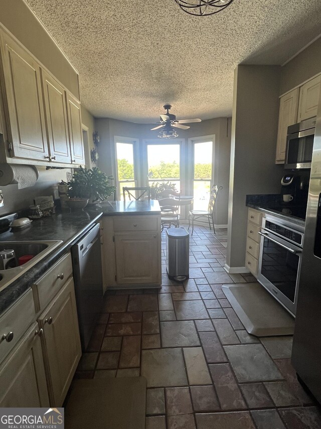 kitchen featuring a healthy amount of sunlight, ceiling fan, a peninsula, and stainless steel appliances