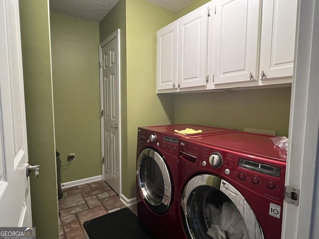washroom with baseboards, stone finish floor, a textured ceiling, independent washer and dryer, and cabinet space