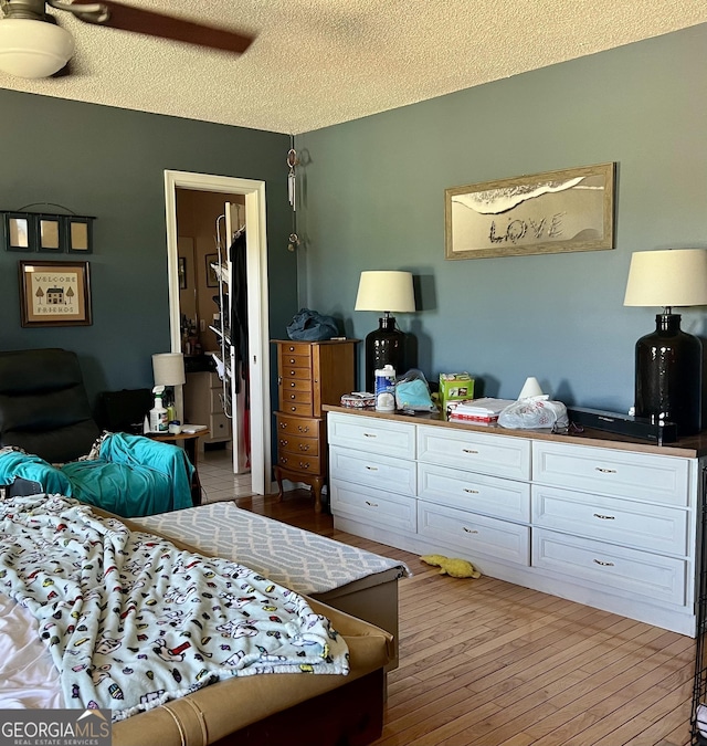 bedroom with a textured ceiling, ceiling fan, and hardwood / wood-style flooring