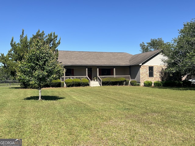 ranch-style home featuring roof with shingles, a front lawn, and covered porch