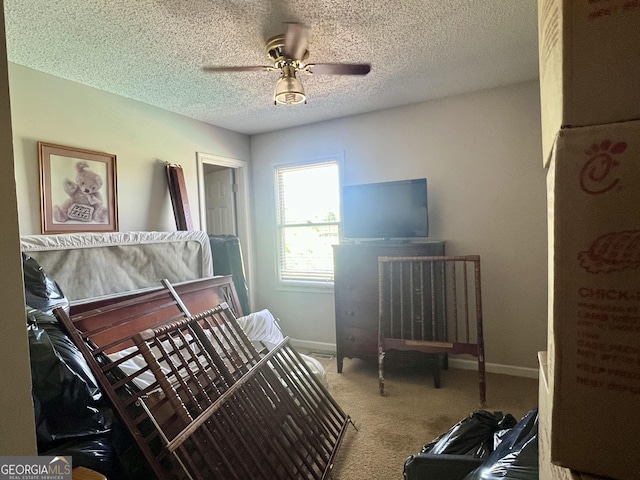 bedroom featuring baseboards, ceiling fan, carpet, and a textured ceiling