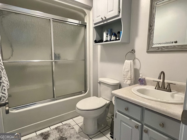 bathroom with toilet, tile patterned floors, vanity, and shower / bath combination with glass door