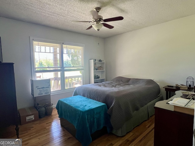 bedroom with ceiling fan, a textured ceiling, and wood finished floors