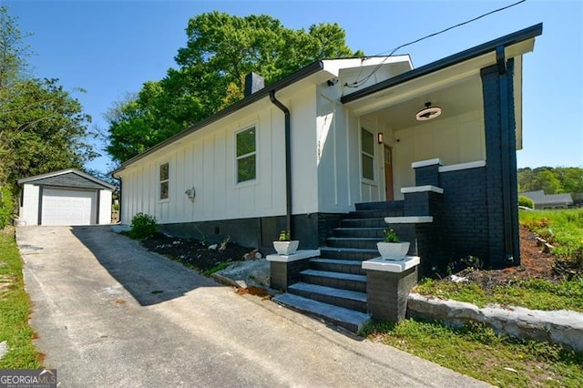 view of front facade with a garage, a chimney, board and batten siding, an outdoor structure, and driveway