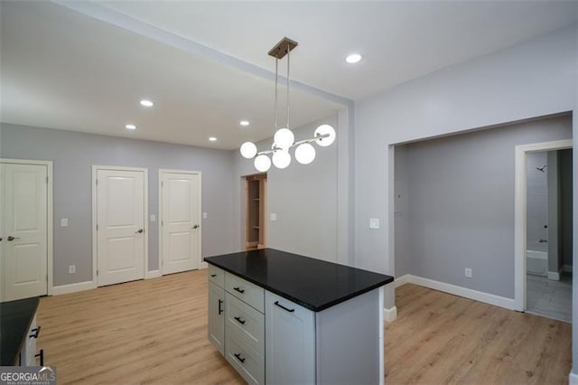 kitchen with white cabinets, light wood-style floors, baseboards, and dark countertops