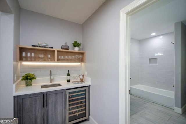 bar featuring a sink, tasteful backsplash, baseboards, indoor wet bar, and beverage cooler