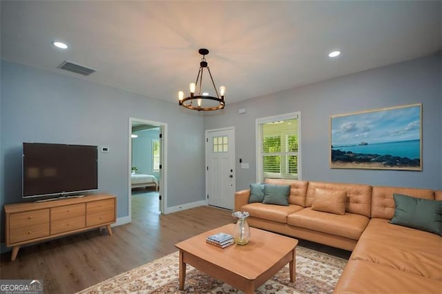 living room featuring visible vents, baseboards, a chandelier, recessed lighting, and wood finished floors