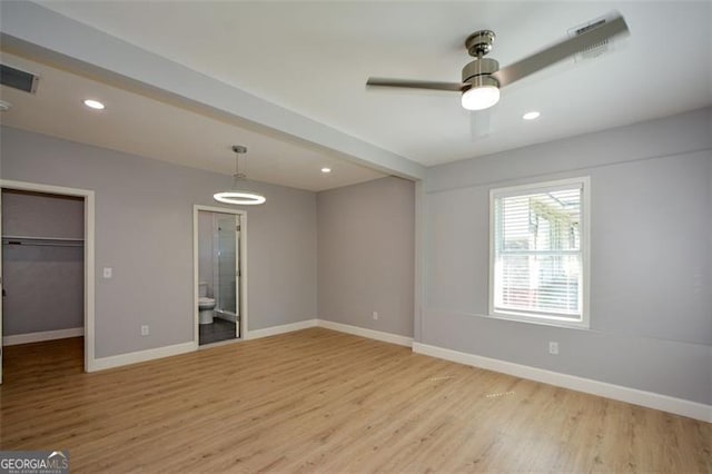 unfurnished bedroom featuring light wood-style flooring, baseboards, a spacious closet, and recessed lighting