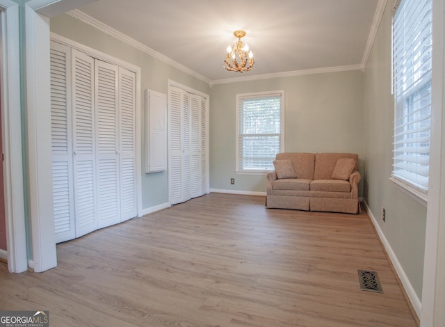 living area featuring ornamental molding, visible vents, light wood-type flooring, and a notable chandelier