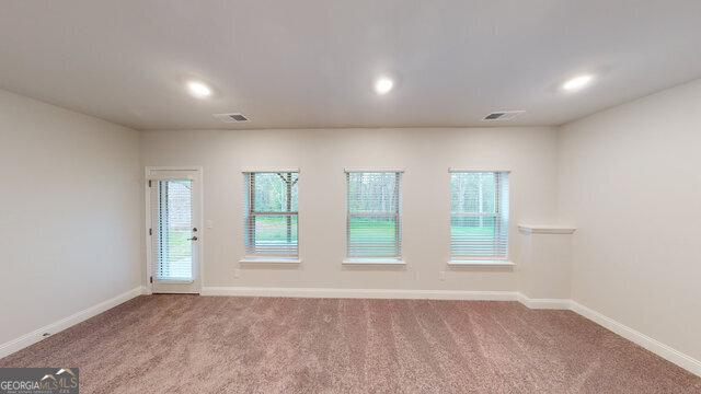 empty room featuring carpet flooring, visible vents, and baseboards