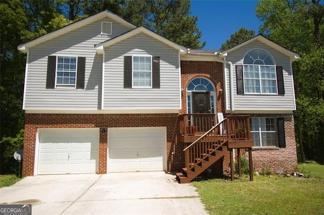 raised ranch featuring an attached garage, driveway, stairway, and brick siding