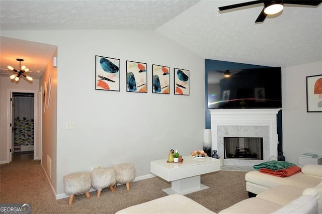 living area featuring ceiling fan with notable chandelier, a high end fireplace, vaulted ceiling, carpet flooring, and baseboards