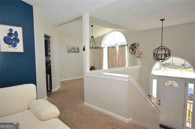 carpeted entryway with baseboards, a notable chandelier, and vaulted ceiling