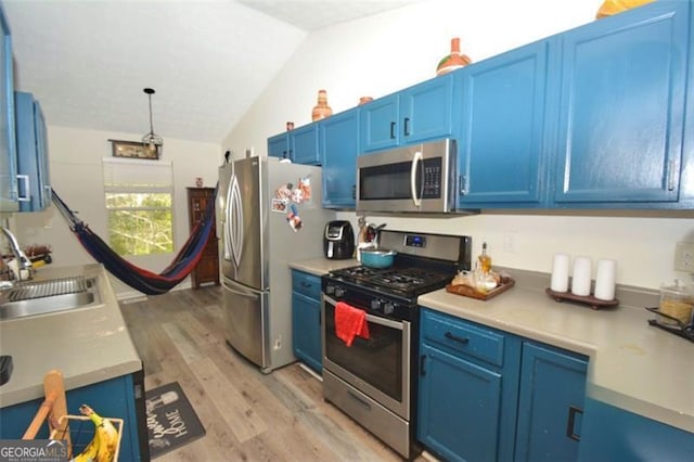 kitchen with light wood-type flooring, vaulted ceiling, blue cabinetry, stainless steel appliances, and a sink