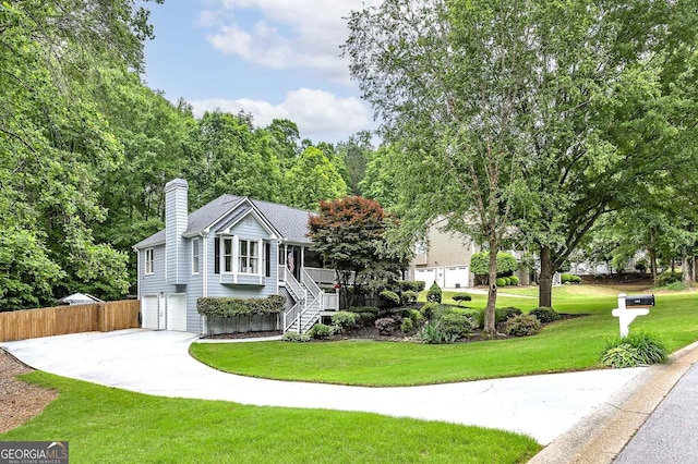 view of front facade with a garage, a front lawn, fence, a chimney, and stairway
