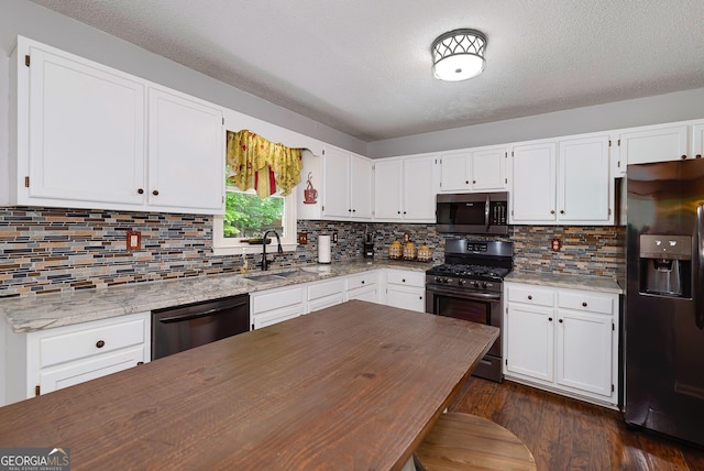 kitchen featuring a sink, light stone counters, white cabinets, and stainless steel appliances