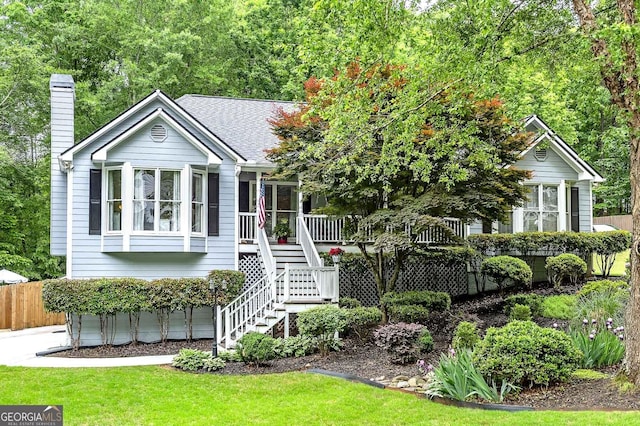 view of front of property with fence, stairs, a chimney, and a front lawn