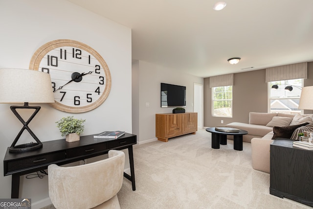 living area featuring light carpet and baseboards