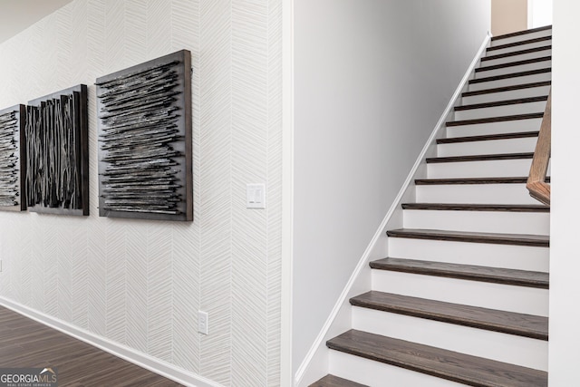 stairway featuring wallpapered walls, wood finished floors, and baseboards