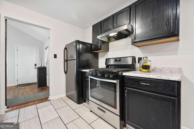 3690 Asbury Ln SW, Atlanta, GA 30331 - kitchen with stainless steel gas range, under cabinet range hood, dark cabinets, freestanding refrigerator, and lofted ceiling