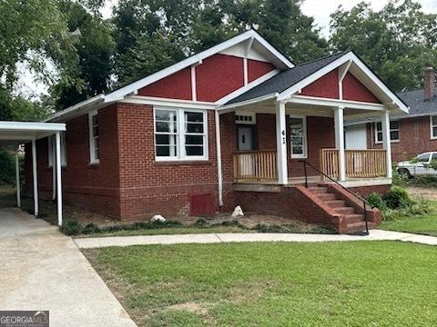 4 I Ave, Gainesville, GA 30504 - view of front of home with covered porch, a carport, a front yard, brick siding, and driveway