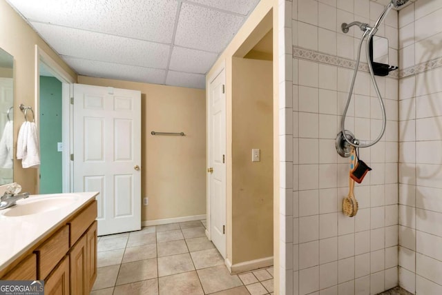 1055 River Bluff Dr, Winder, GA 30680 - bathroom with vanity, baseboards, tile patterned flooring, a drop ceiling, and a tile shower