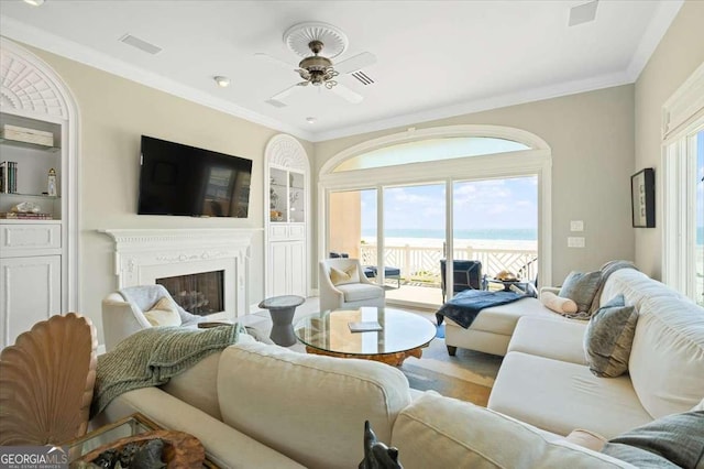 living room featuring wood finished floors, a glass covered fireplace, a ceiling fan, and visible vents