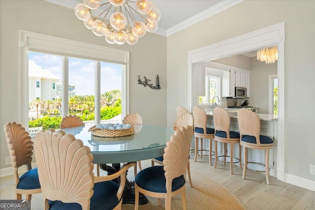 dining room featuring crown molding, light wood-style floors, an inviting chandelier, baseboards, and plenty of natural light