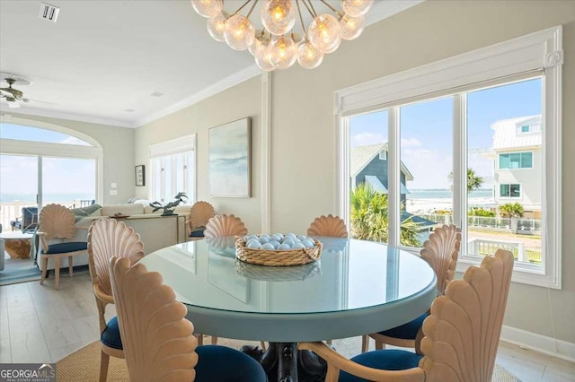 dining room with a wealth of natural light, visible vents, crown molding, and light wood-style flooring