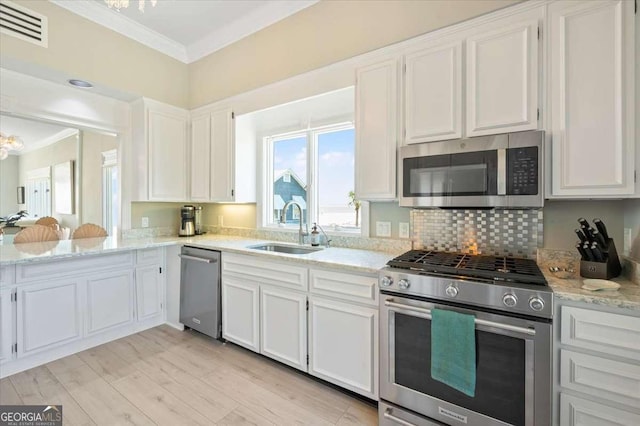 kitchen featuring visible vents, a sink, ornamental molding, appliances with stainless steel finishes, and white cabinetry