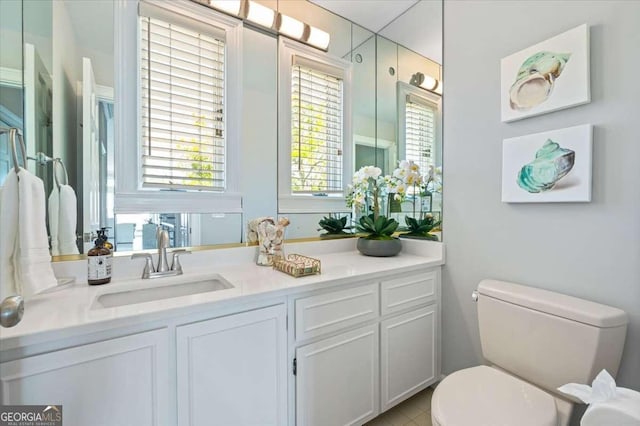 bathroom featuring toilet, vanity, and plenty of natural light