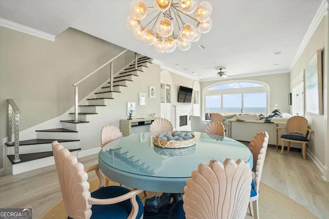 dining area with light wood finished floors, baseboards, ornamental molding, and stairway
