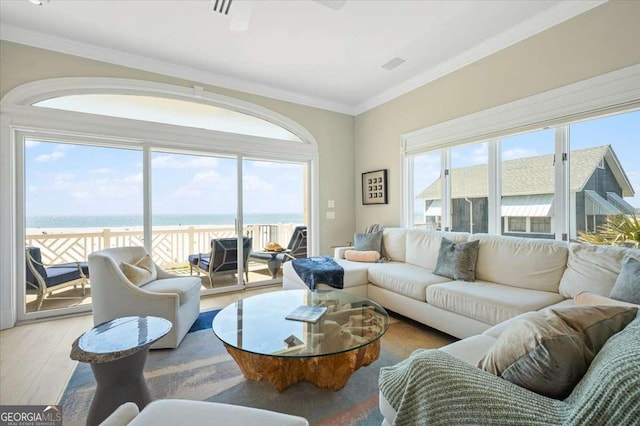 living room featuring a water view, ornamental molding, visible vents, and wood finished floors