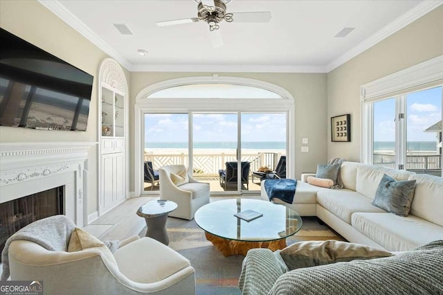living area with a water view, visible vents, ornamental molding, and wood finished floors