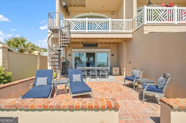 view of patio featuring outdoor dining space, stairway, and fence