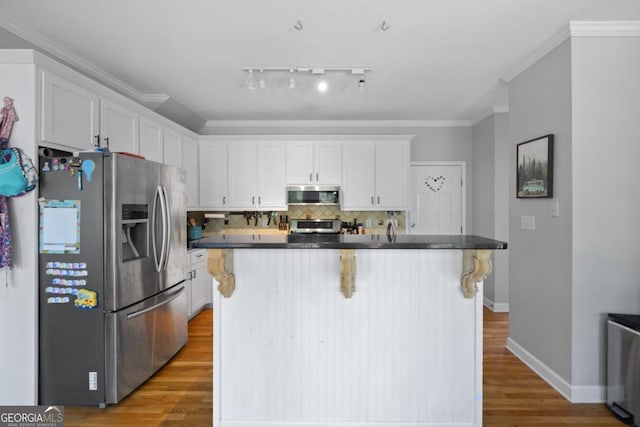 4016 Upland Trce, Marietta, GA 30066 - kitchen featuring white cabinets, dark countertops, wood finished floors, stainless steel appliances, and a breakfast bar area