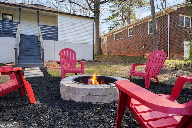 view of yard featuring a fire pit, covered porch, and stairs