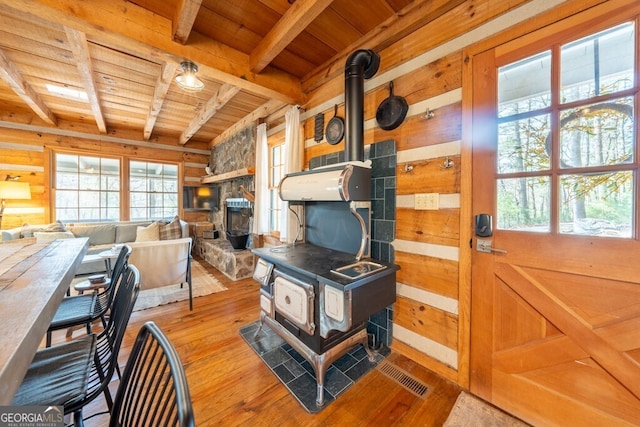 interior space featuring wood ceiling, a wood stove, hardwood / wood-style floors, and beam ceiling