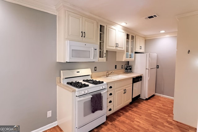 1181 Church St Unit D, Decatur, GA 30030 - kitchen featuring white appliances, light countertops, light wood-style flooring, glass insert cabinets, and ornamental molding