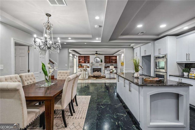 dining area featuring visible vents, a fireplace, marble finish floor, and a raised ceiling