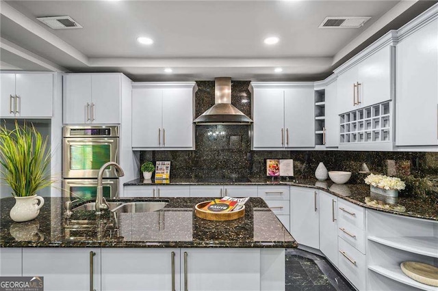 kitchen featuring stainless steel double oven, open shelves, a sink, wall chimney exhaust hood, and white cabinetry