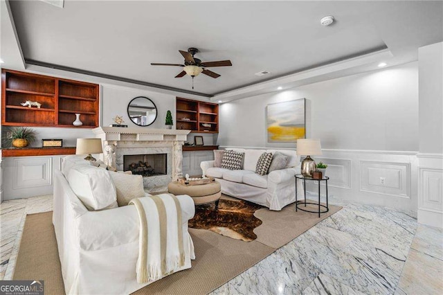 living room featuring recessed lighting, a wainscoted wall, marble finish floor, a premium fireplace, and ceiling fan