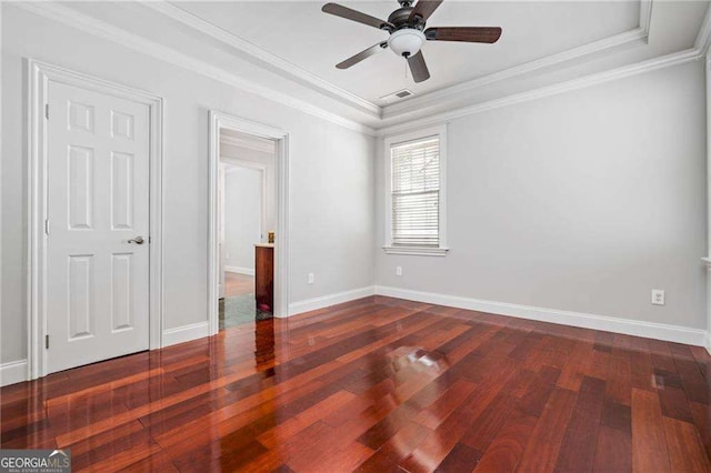 unfurnished bedroom featuring baseboards, visible vents, a raised ceiling, and dark wood-style flooring