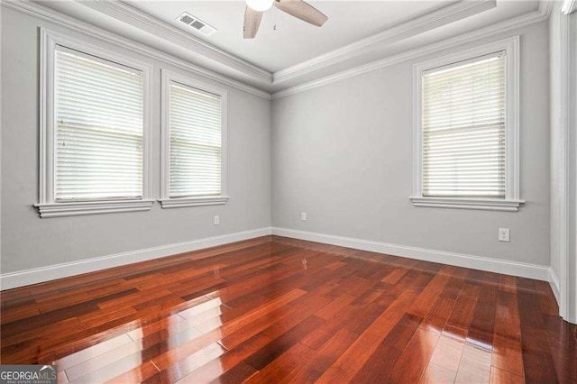 spare room featuring dark wood finished floors, baseboards, visible vents, ceiling fan, and crown molding