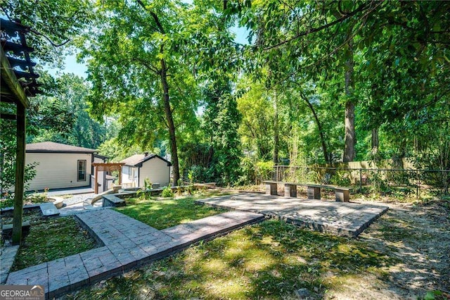 view of yard featuring a patio area, an outbuilding, and fence