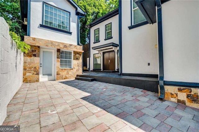 exterior space featuring stone siding, a patio area, and stucco siding